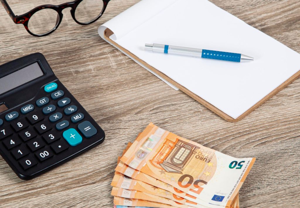 gotówka leżąca na biurka obok kalkulatora i notatnika